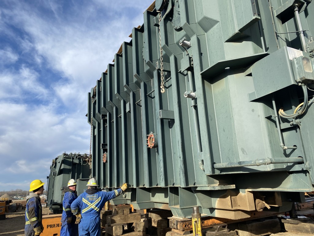 Workers inspecting large surplus transformer